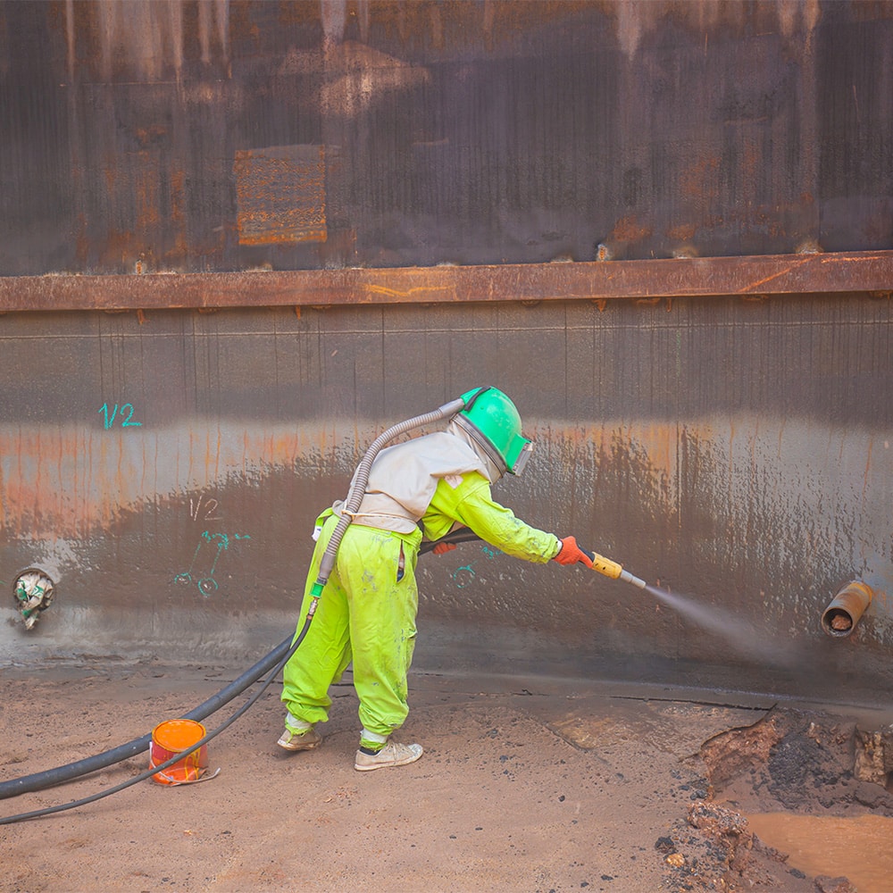 worker preparing surface for protection from uniform corrosion