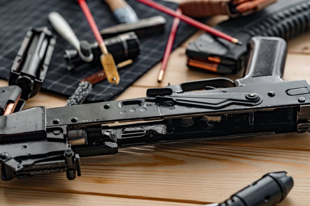 A gun that is disassembled laying on a table with its parts