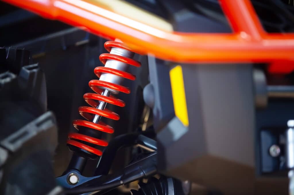 A close-up of a red spring that acts as a suspension for a vehicle