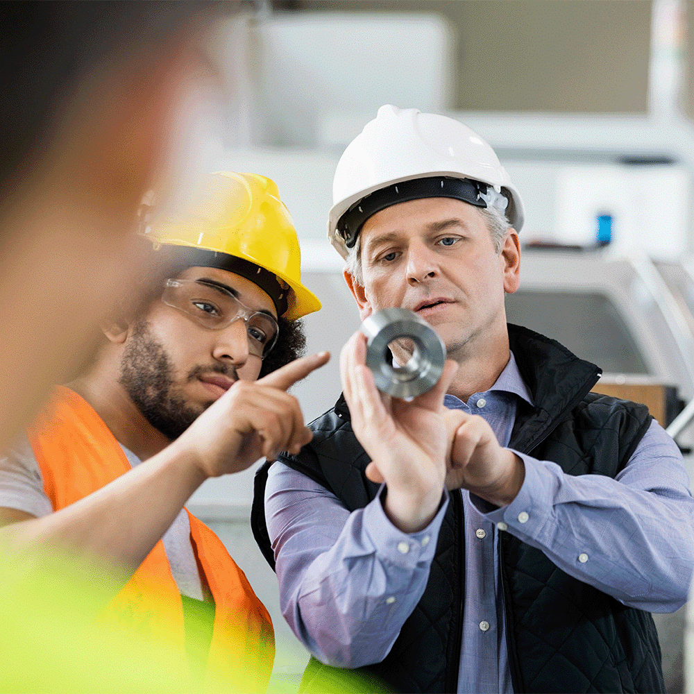 Engineers inspect a metal component as part of ISO 9001:2015 quality management system standard.