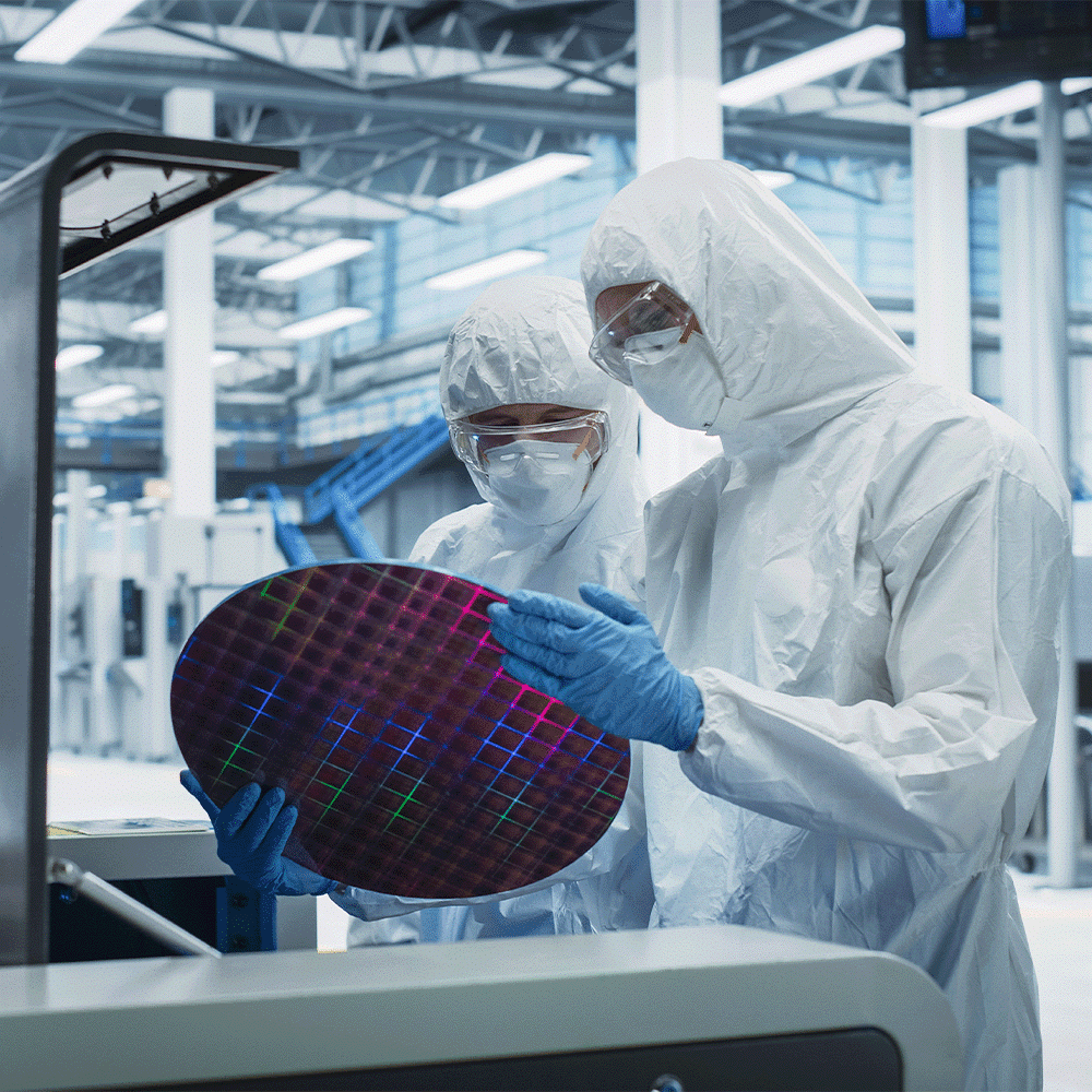 Two laboratory technicians inspect a semiconductor component as part of the requirements for achieving ISO 9001 certification for quality management.