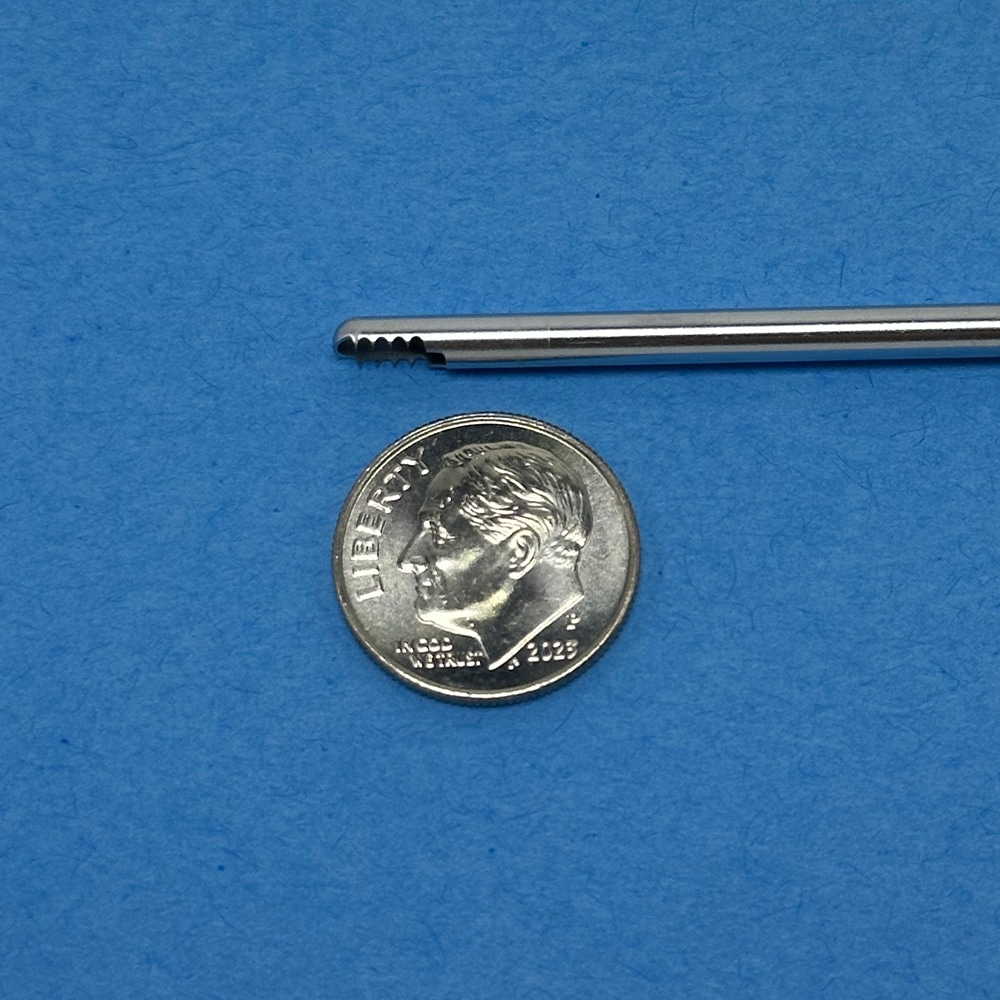 Arthroscopic shaver outer tube with cutting window and teeth next to a U.S. dime (17.91 mm diameter), illustrating how microns of coating thickness affect clearance.