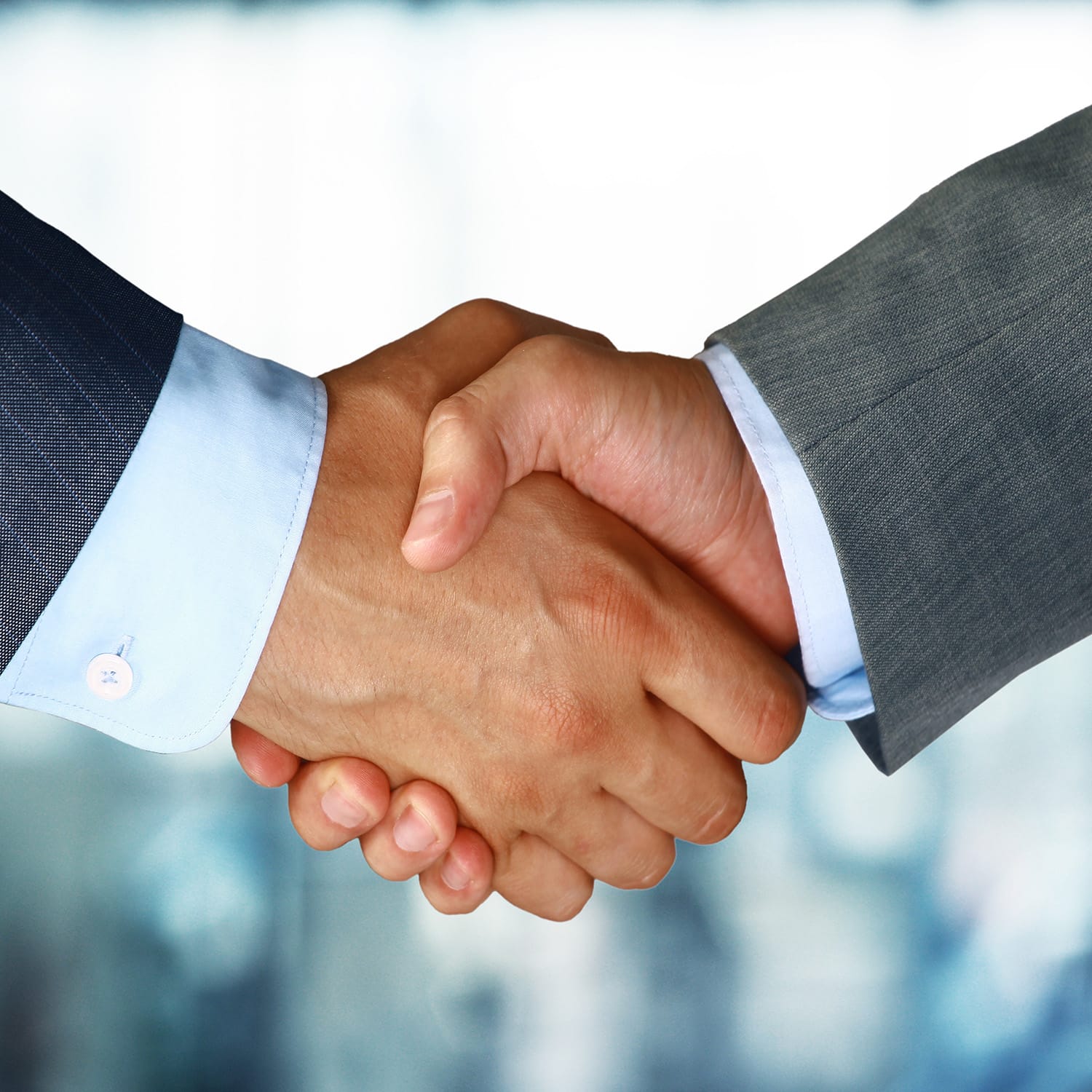 Close-up of two people in business suits shaking hands, symbolizing an agreement or partnership.