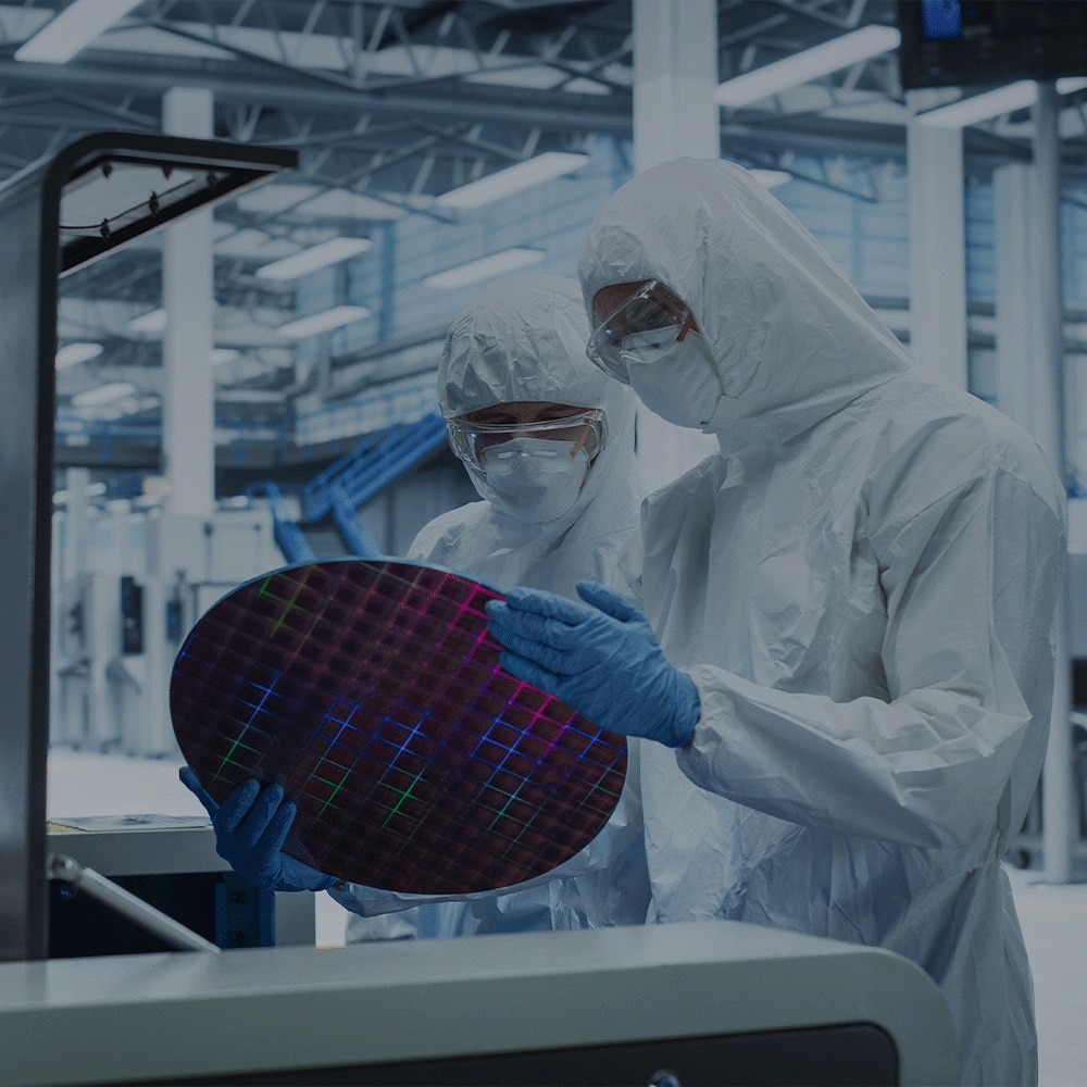 two technicians holding a large semiconductor wafer